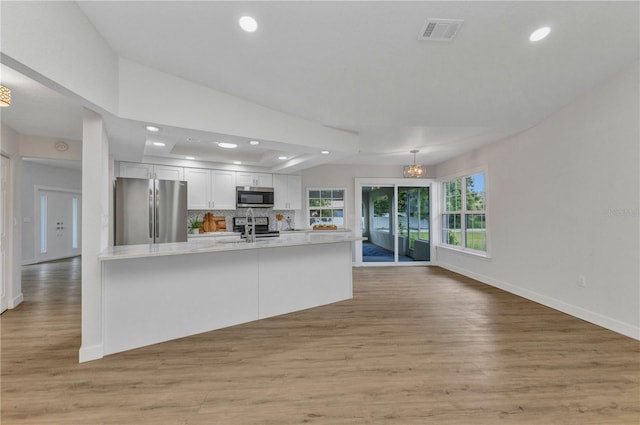 229 Waterside St, Port Charlotte, FL 33954 - kitchen with stainless steel appliances, white cabinetry, light countertops, light wood-style flooring, and backsplash