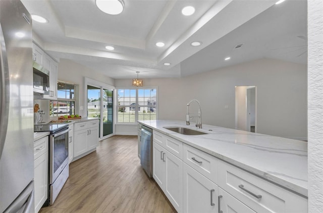 229 Waterside St, Port Charlotte, FL 33954 - kitchen featuring stainless steel appliances, white cabinets, light wood finished floors, light stone counters, and a raised ceiling
