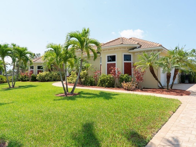 6057 Calusa Ridge Trl, Bokeelia, FL 33922 - mediterranean / spanish home featuring a front lawn, a tiled roof, driveway, stucco siding, and an attached garage