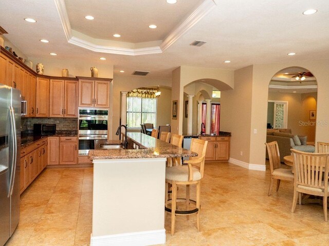 6057 Calusa Ridge Trl, Bokeelia, FL 33922 - kitchen featuring appliances with stainless steel finishes, arched walkways, a tray ceiling, recessed lighting, and crown molding