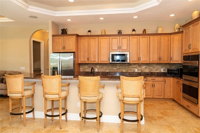 6057 Calusa Ridge Trl, Bokeelia, FL 33922 - kitchen with appliances with stainless steel finishes, a raised ceiling, crown molding, backsplash, and arched walkways