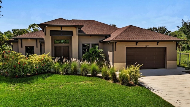 5451 Prime Ter, North Port, FL 34286 - view of front facade with an attached garage, decorative driveway, a front lawn, stucco siding, and roof with shingles