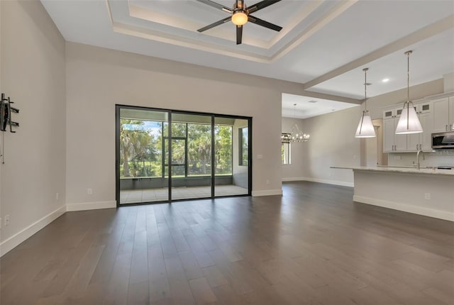 5451 Prime Ter, North Port, FL 34286 - unfurnished living room featuring a raised ceiling, ceiling fan, baseboards, dark wood-style flooring, and recessed lighting