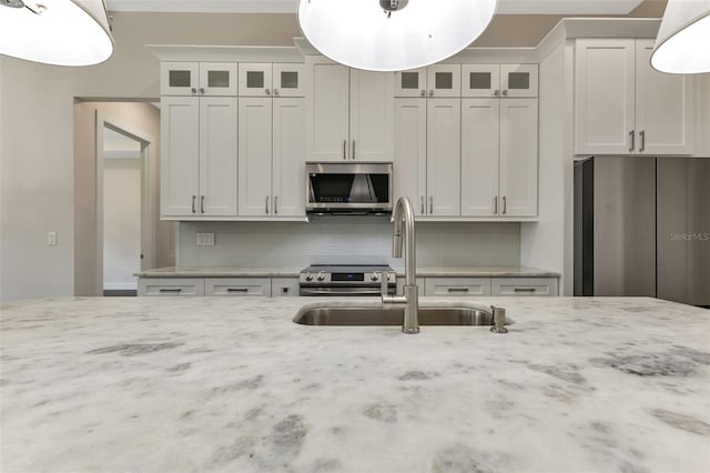 5451 Prime Ter, North Port, FL 34286 - kitchen featuring appliances with stainless steel finishes, a sink, decorative backsplash, and light stone counters