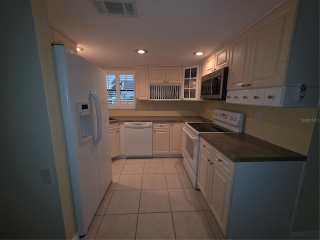 311 Garvin St Unit 405B, Punta Gorda, FL 33950 - kitchen featuring white appliances, dark countertops, light tile patterned flooring, white cabinetry, and glass insert cabinets