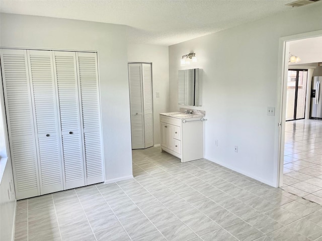 13100 S Mccall Rd Unit 125, Port Charlotte, FL 33981 - unfurnished bedroom with light tile patterned flooring, stainless steel refrigerator with ice dispenser, a sink, a textured ceiling, and baseboards