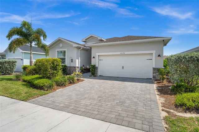 16176 Lotus Way, Punta Gorda, FL 33982 - ranch-style home featuring stone siding, decorative driveway, stucco siding, and an attached garage