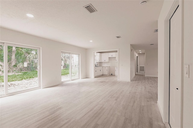 37 Oakland Hills Ct, Rotonda West, FL 33947 - unfurnished living room featuring light wood-type flooring, baseboards, a sink, and recessed lighting