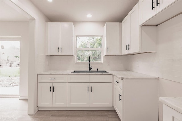 37 Oakland Hills Ct, Rotonda West, FL 33947 - kitchen featuring a sink, decorative backsplash, white cabinets, recessed lighting, and light wood-type flooring
