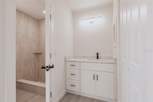 37 Oakland Hills Ct, Rotonda West, FL 33947 - bathroom with wood finished floors, tiled shower, vanity, and baseboards