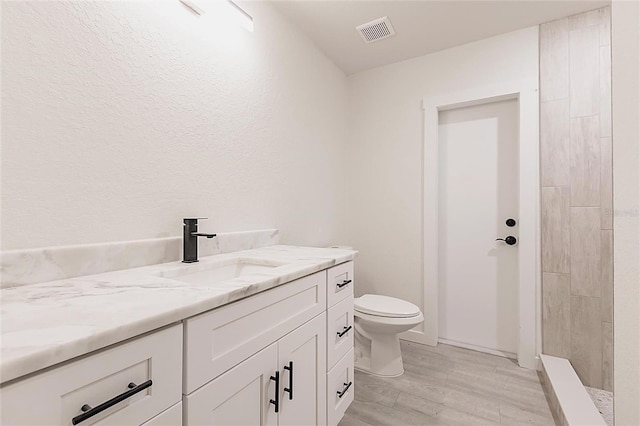 37 Oakland Hills Ct, Rotonda West, FL 33947 - bathroom with vanity, toilet, wood finished floors, and tiled shower