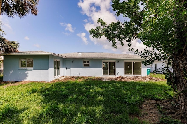 37 Oakland Hills Ct, Rotonda West, FL 33947 - rear view of house featuring stucco siding and a lawn