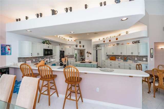 17400 White Water Ct, Punta Gorda, FL 33982 - kitchen featuring black appliances, decorative backsplash, a breakfast bar area, a peninsula, and light countertops