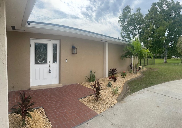 26129 Madras Ct, Punta Gorda, FL 33983 - doorway to property with stucco siding and a lawn