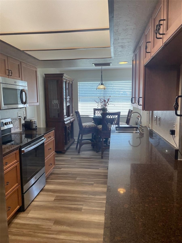 26129 Madras Ct, Punta Gorda, FL 33983 - kitchen featuring stainless steel appliances, a sink, light wood-style floors, dark stone countertops, and a textured ceiling