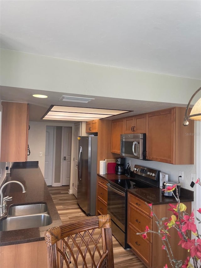 26129 Madras Ct, Punta Gorda, FL 33983 - kitchen featuring appliances with stainless steel finishes, a sink, light wood-style floors, and brown cabinetry