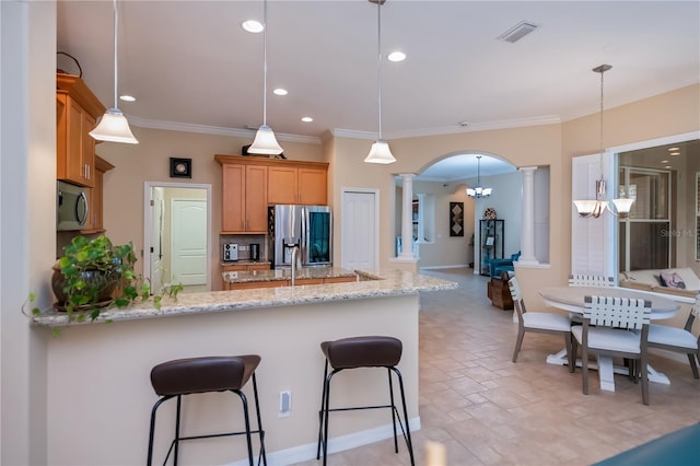 1062 Eagles Flight Way, North Port, FL 34287 - kitchen featuring ornate columns, stainless steel appliances, a peninsula, arched walkways, and a breakfast bar area