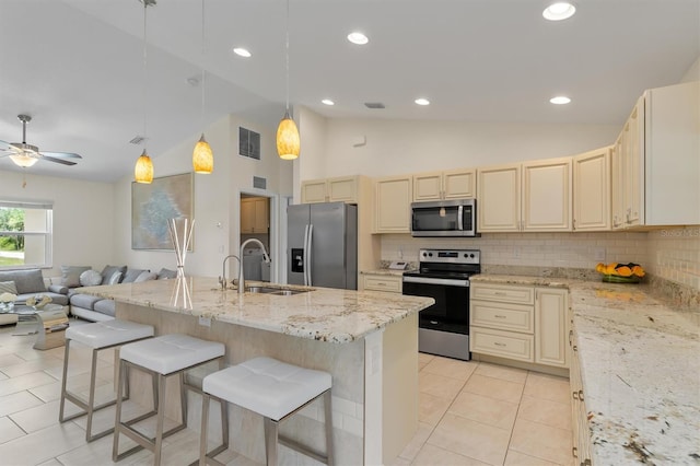 3138 Darius Ave, North Port, FL 34288 - kitchen with stainless steel appliances, a sink, vaulted ceiling, cream cabinetry, and tasteful backsplash