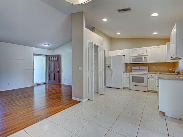 4609 Jaslo Ave, North Port, FL 34286 - kitchen with white appliances, vaulted ceiling, a sink, white cabinets, and light tile patterned flooring