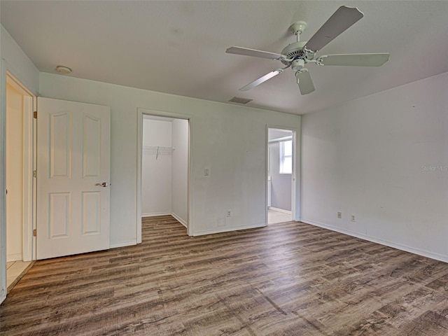 4609 Jaslo Ave, North Port, FL 34286 - unfurnished bedroom with wood finished floors, a walk in closet, a closet, baseboards, and a ceiling fan