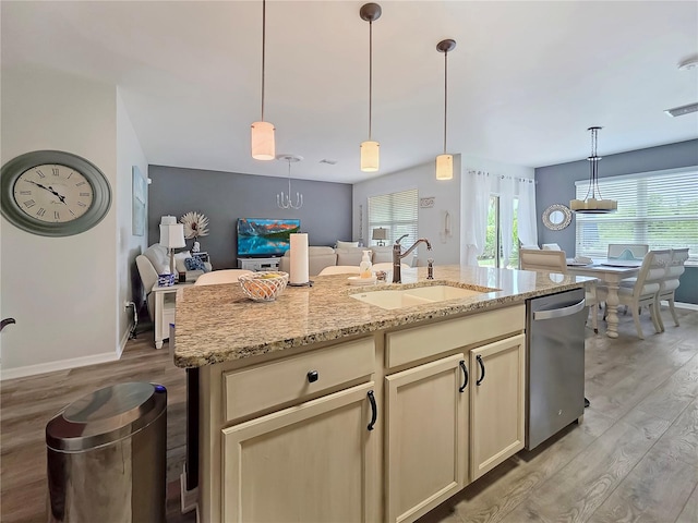 7292 Mikasa Dr, Punta Gorda, FL 33950 - kitchen featuring stainless steel dishwasher, a sink, light wood-type flooring, light stone countertops, and baseboards