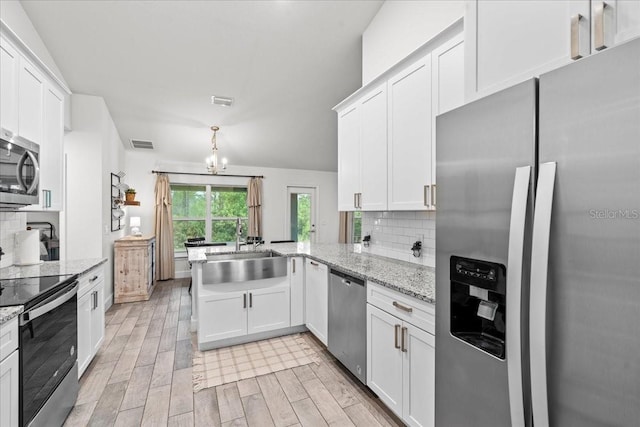 5436 Jessamine Ave, North Port, FL 34291 - kitchen with appliances with stainless steel finishes, a sink, a peninsula, backsplash, and white cabinetry