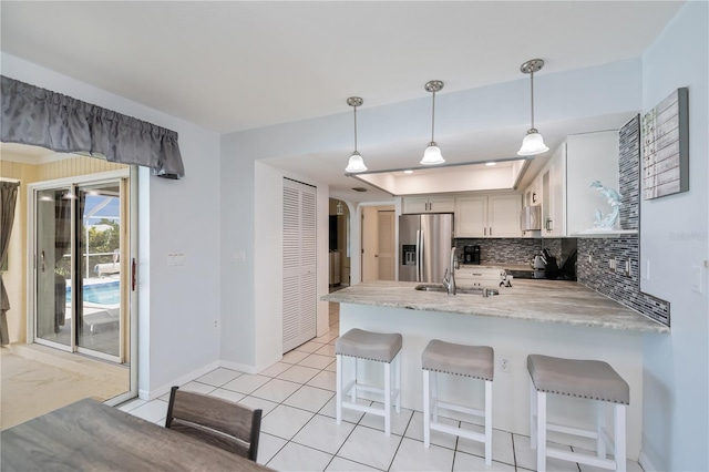 1 Sportsman Cir, Rotonda West, FL 33947 - kitchen with stainless steel refrigerator with ice dispenser, a peninsula, backsplash, and hanging light fixtures