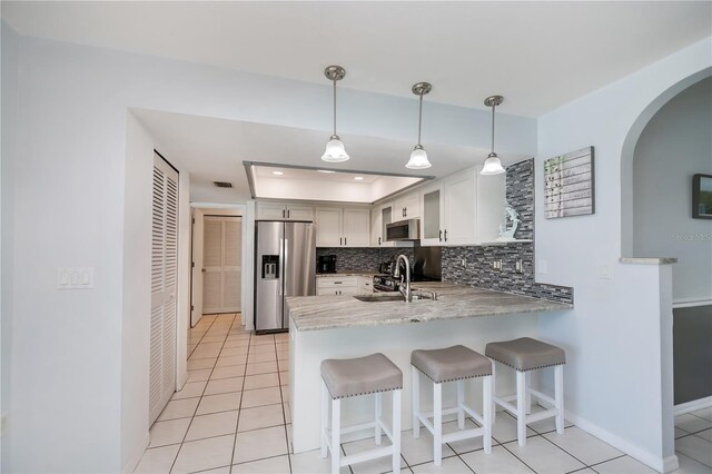 1 Sportsman Cir, Rotonda West, FL 33947 - kitchen featuring stainless steel appliances, a peninsula, light tile patterned floors, a breakfast bar area, and tasteful backsplash