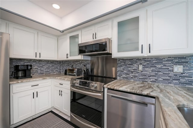 1 Sportsman Cir, Rotonda West, FL 33947 - kitchen with appliances with stainless steel finishes, tile patterned flooring, white cabinets, and decorative backsplash