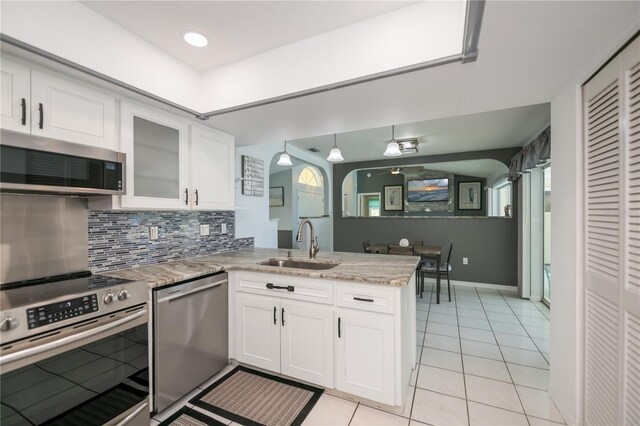 1 Sportsman Cir, Rotonda West, FL 33947 - kitchen with stainless steel appliances, a peninsula, white cabinets, decorative backsplash, and light tile patterned floors