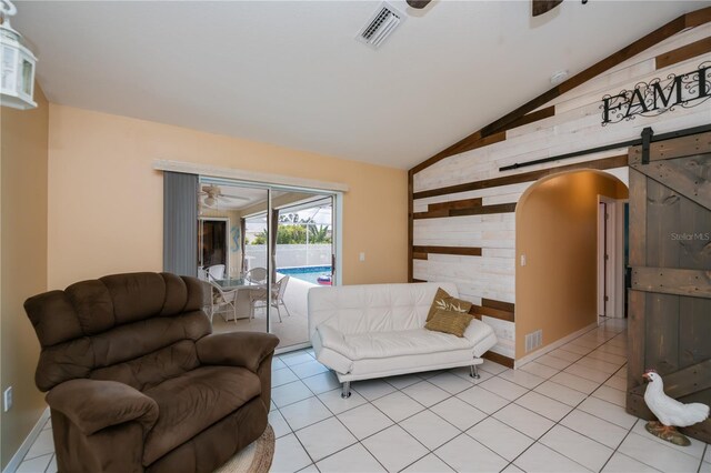 1 Sportsman Cir, Rotonda West, FL 33947 - living area with ceiling fan, wood walls, vaulted ceiling, arched walkways, and a barn door