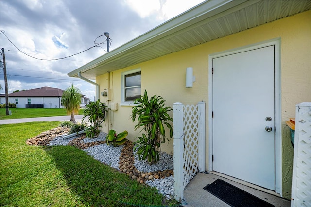 1 Sportsman Cir, Rotonda West, FL 33947 - view of exterior entry featuring stucco siding and a lawn