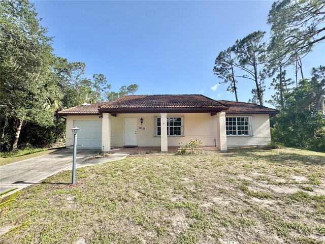 18335 Oxford Ave, Port Charlotte, FL 33948 - view of front of home featuring stucco siding, a tile roof, concrete driveway, a garage, and a front lawn