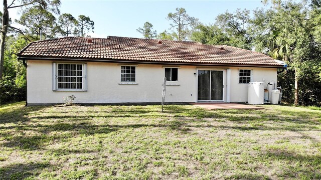 18335 Oxford Ave, Port Charlotte, FL 33948 - rear view of property with a lawn, a tiled roof, stucco siding, and a patio
