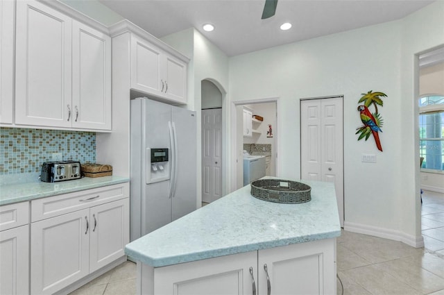 1499 Nuremberg Blvd, Punta Gorda, FL 33983 - kitchen with white refrigerator with ice dispenser, separate washer and dryer, light tile patterned floors, white cabinetry, and decorative backsplash