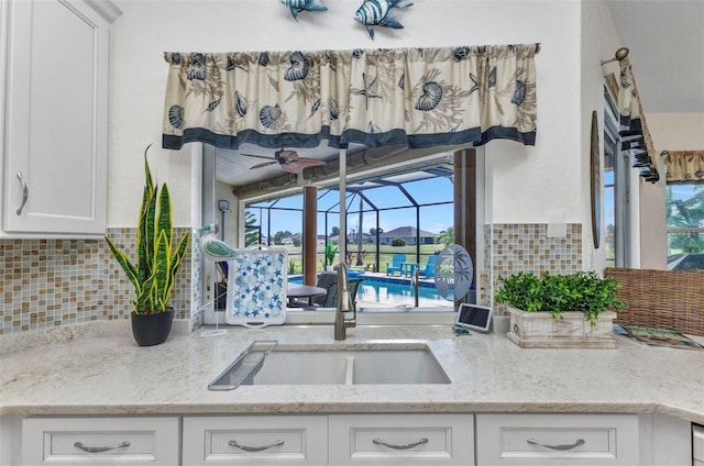1499 Nuremberg Blvd, Punta Gorda, FL 33983 - kitchen featuring tasteful backsplash, white cabinets, light stone countertops, and a sink