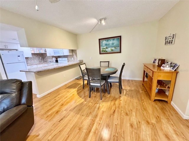 1515 Forrest Nelson Blvd Unit D102, Port Charlotte, FL 33952 - dining space with light wood-style floors, a textured ceiling, and baseboards