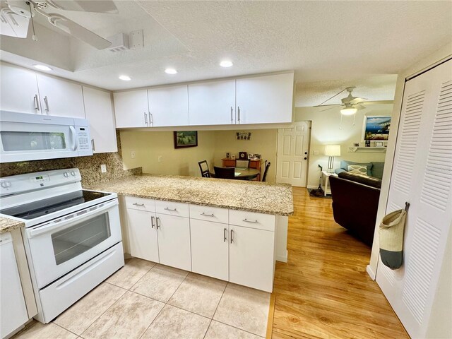 1515 Forrest Nelson Blvd Unit D102, Port Charlotte, FL 33952 - kitchen with white appliances, a ceiling fan, white cabinets, a textured ceiling, and a peninsula