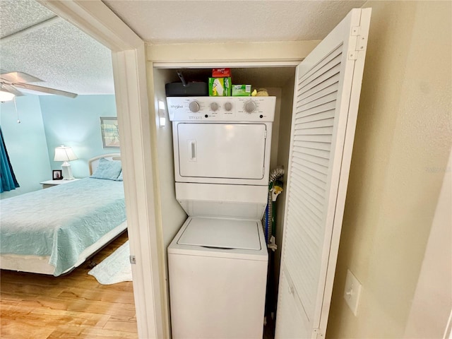 1515 Forrest Nelson Blvd Unit D102, Port Charlotte, FL 33952 - washroom featuring estacked washer and dryer, ceiling fan, wood finished floors, and a textured ceiling