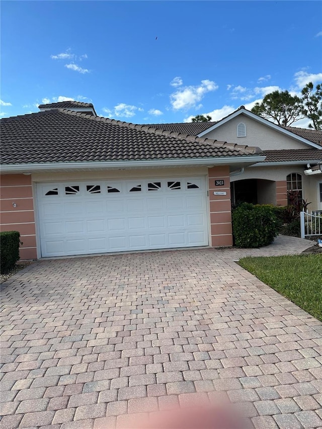 2023 Lynx Run, North Port, FL 34288 - view of front of home with decorative driveway, an attached garage, stucco siding, and a tiled roof