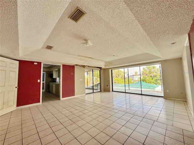 1611 Robbins Rd, Nokomis, FL 34275 - empty room with light tile patterned floors, a textured ceiling, a raised ceiling, and baseboards