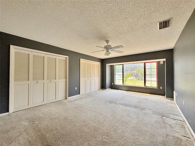 1611 Robbins Rd, Nokomis, FL 34275 - unfurnished bedroom featuring two closets, carpet flooring, a textured ceiling, baseboards, and ceiling fan