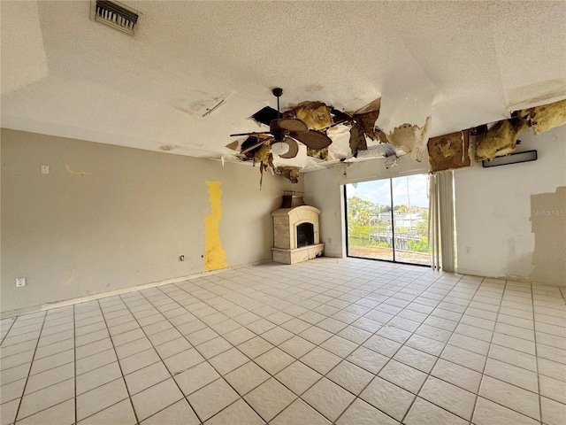 1611 Robbins Rd, Nokomis, FL 34275 - unfurnished living room featuring ceiling fan, a textured ceiling, a fireplace with raised hearth, and tile patterned floors