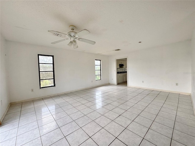1611 Robbins Rd, Nokomis, FL 34275 - empty room with a ceiling fan, light tile patterned floors, a textured ceiling, and baseboards