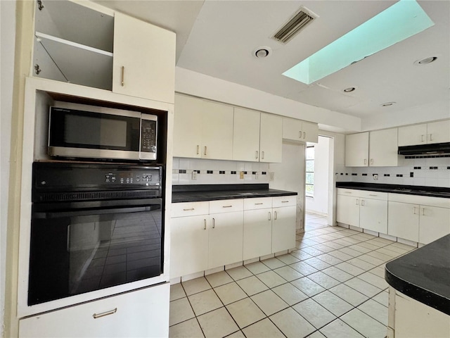 1611 Robbins Rd, Nokomis, FL 34275 - kitchen featuring stainless steel microwave, oven, under cabinet range hood, tasteful backsplash, and a skylight
