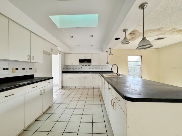 1611 Robbins Rd, Nokomis, FL 34275 - kitchen with a sink, dark countertops, backsplash, a peninsula, and a skylight