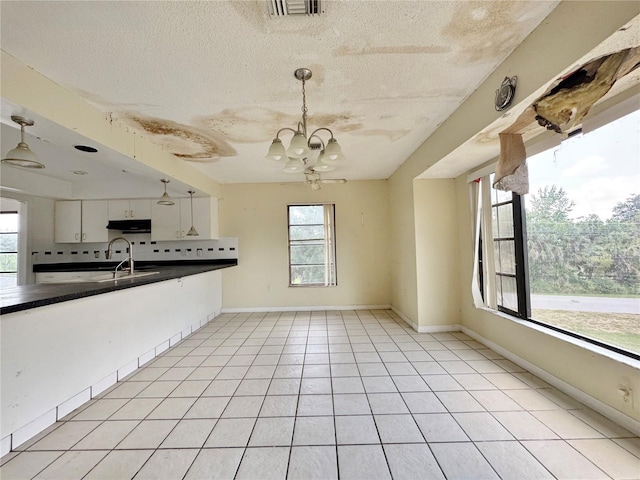 1611 Robbins Rd, Nokomis, FL 34275 - kitchen featuring dark countertops, under cabinet range hood, decorative backsplash, hanging light fixtures, and a chandelier