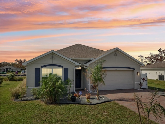 ranch-style home with decorative driveway, a front yard, a garage, and stucco siding