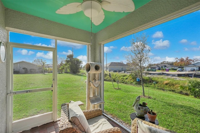 sunroom / solarium with a ceiling fan and a residential view