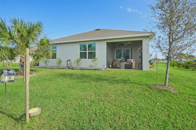 back of property featuring ceiling fan, stucco siding, an outdoor living space, and a lawn